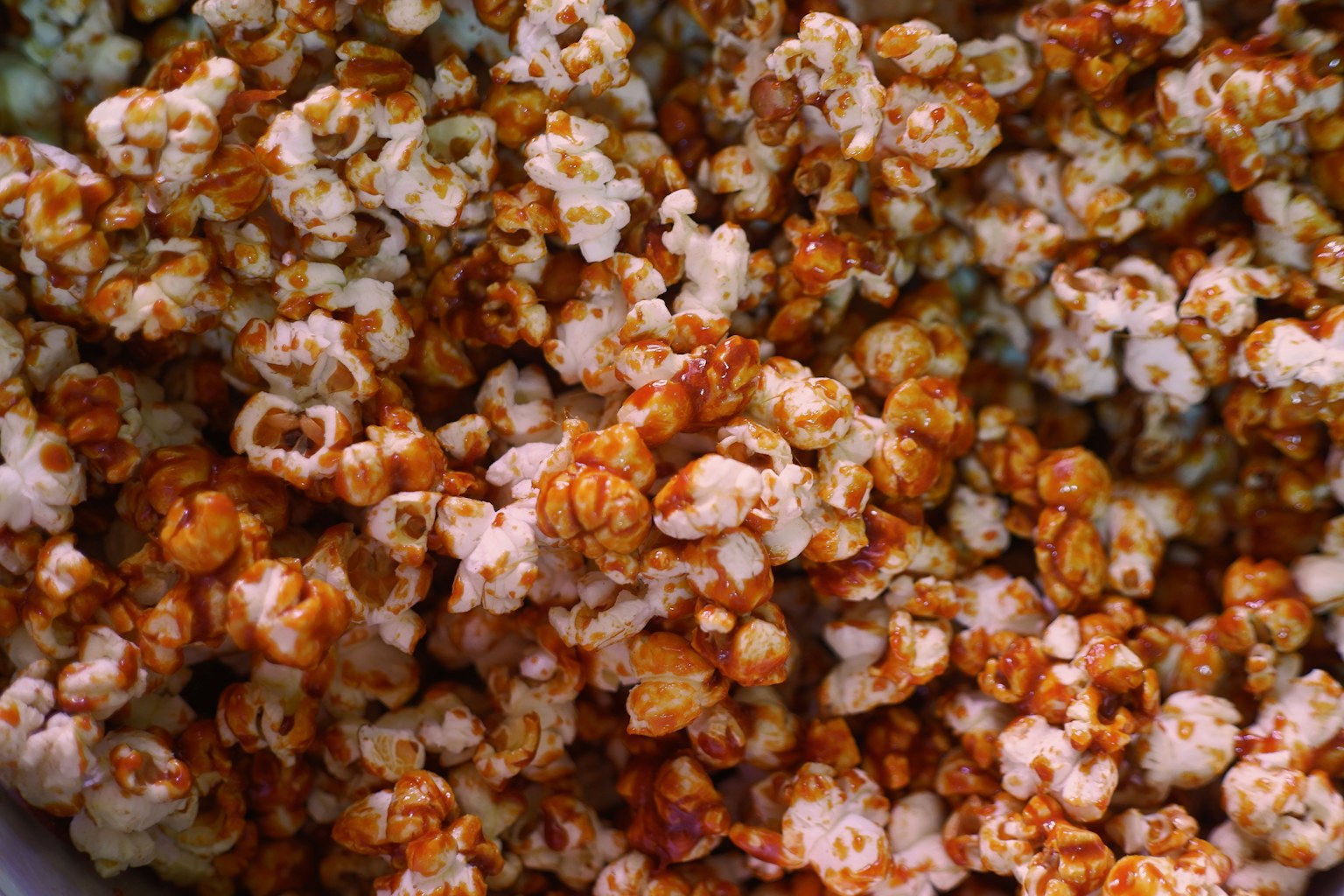 A close-up of glossy caramel-coated popcorn, warm golden kernels filling the frame