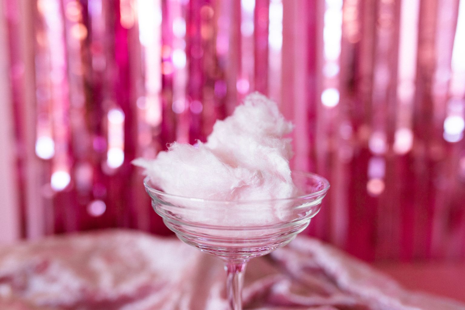 Fairy floss served in a clear glass against a festive pink backdrop