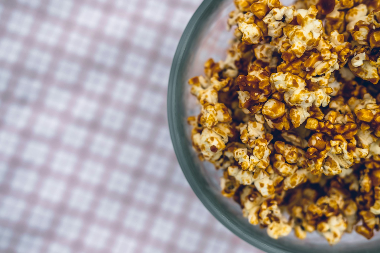 A bowl of warm caramel popcorn on a soft patterned cloth